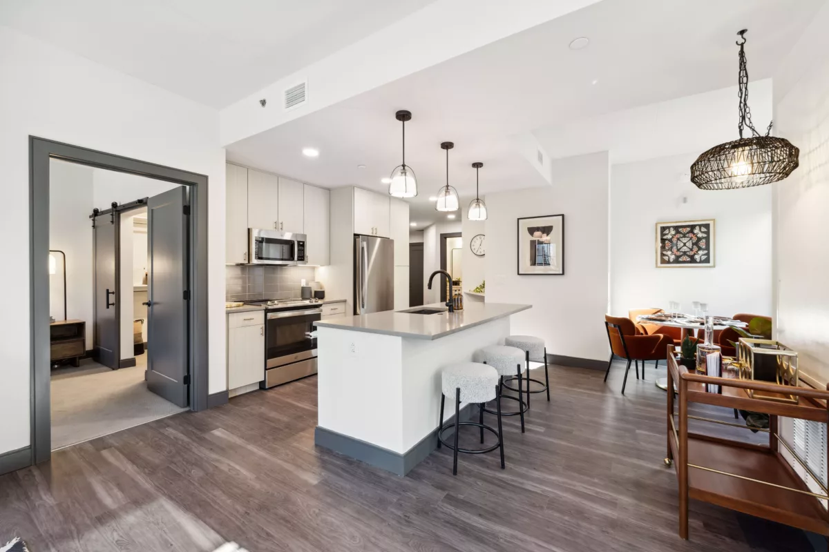 Kitchen with light colored cabinets, dark wood-style floors, and center island with lights hanging above