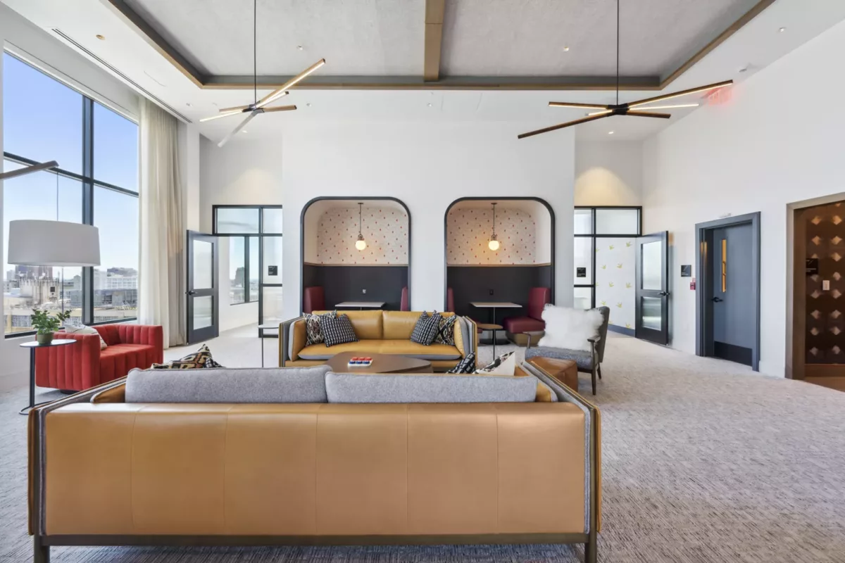 Rooftop lounge with couches, booth seating, and large windows with city views