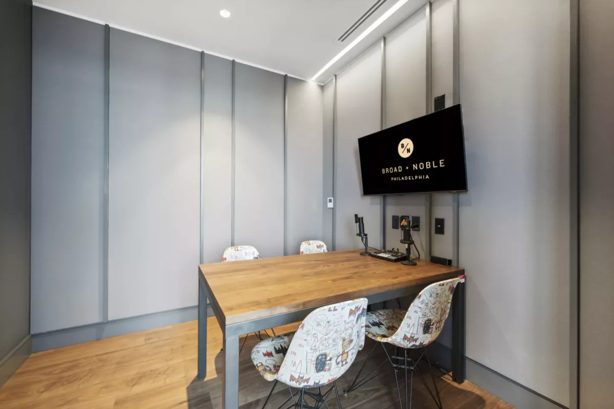 Private podcast studio with table, chairs, audio equipment, and TV screen