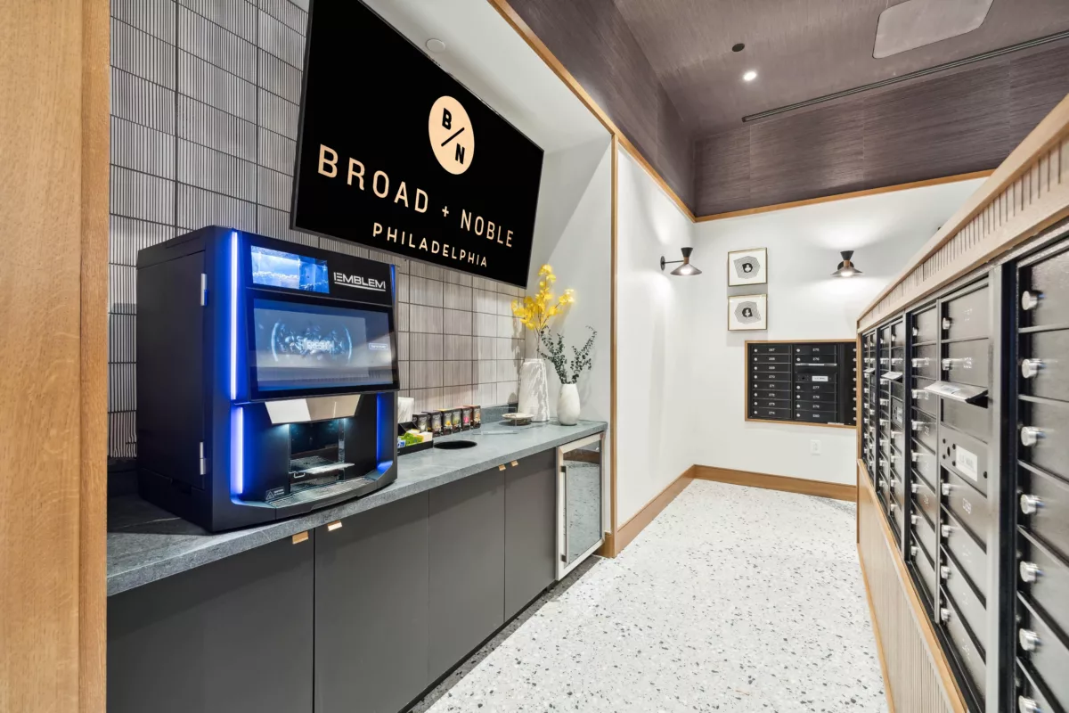 Mail room with black mailboxes and coffee bar with coffee machine and TV screen